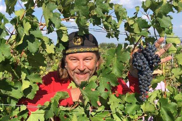 Winzer Andreas Nikolai mit Weintraube im Weinberg